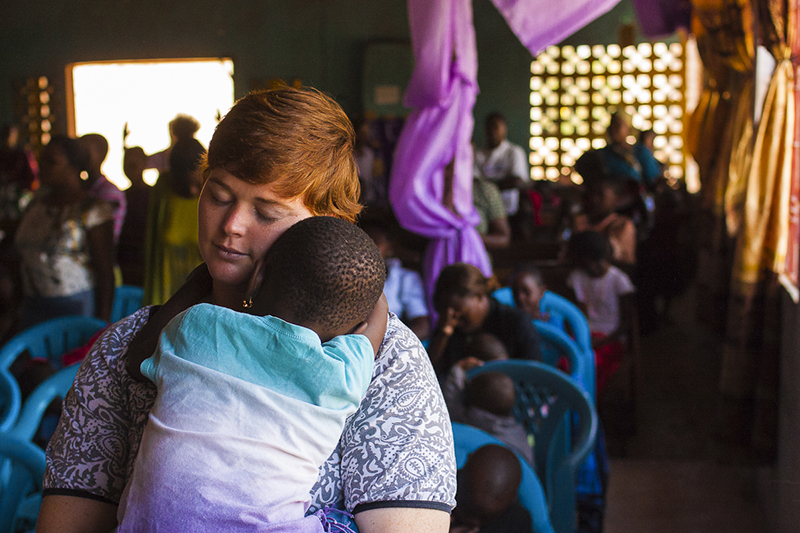 Racer holding a sleeping Kenyan child during a church gathering