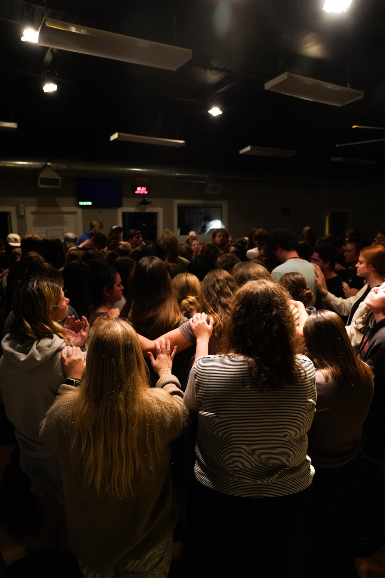 A crowded room of racers gathered shoulder to shoulder in prayer