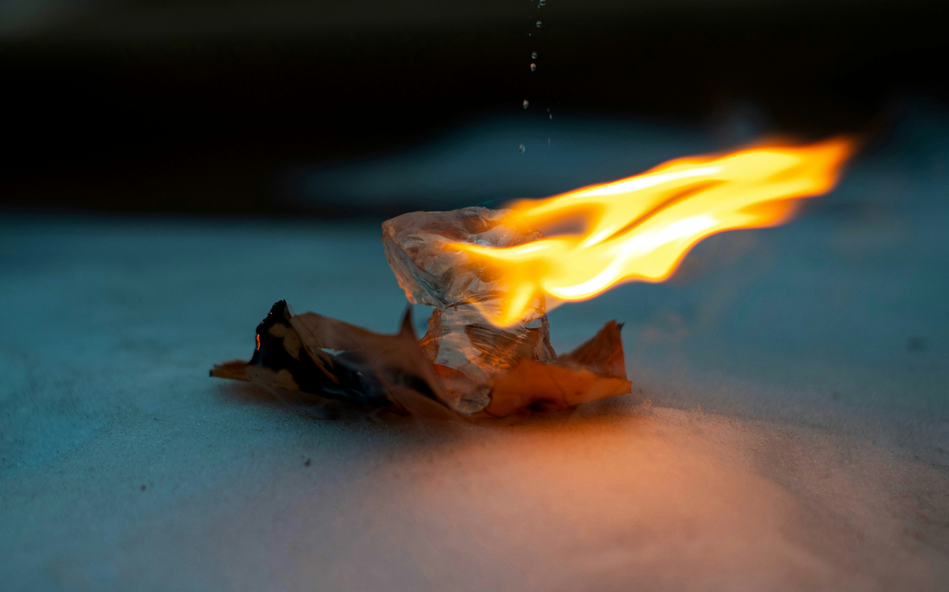 Night shot, faces lit by firelight, someone releasing a paper into the flames.