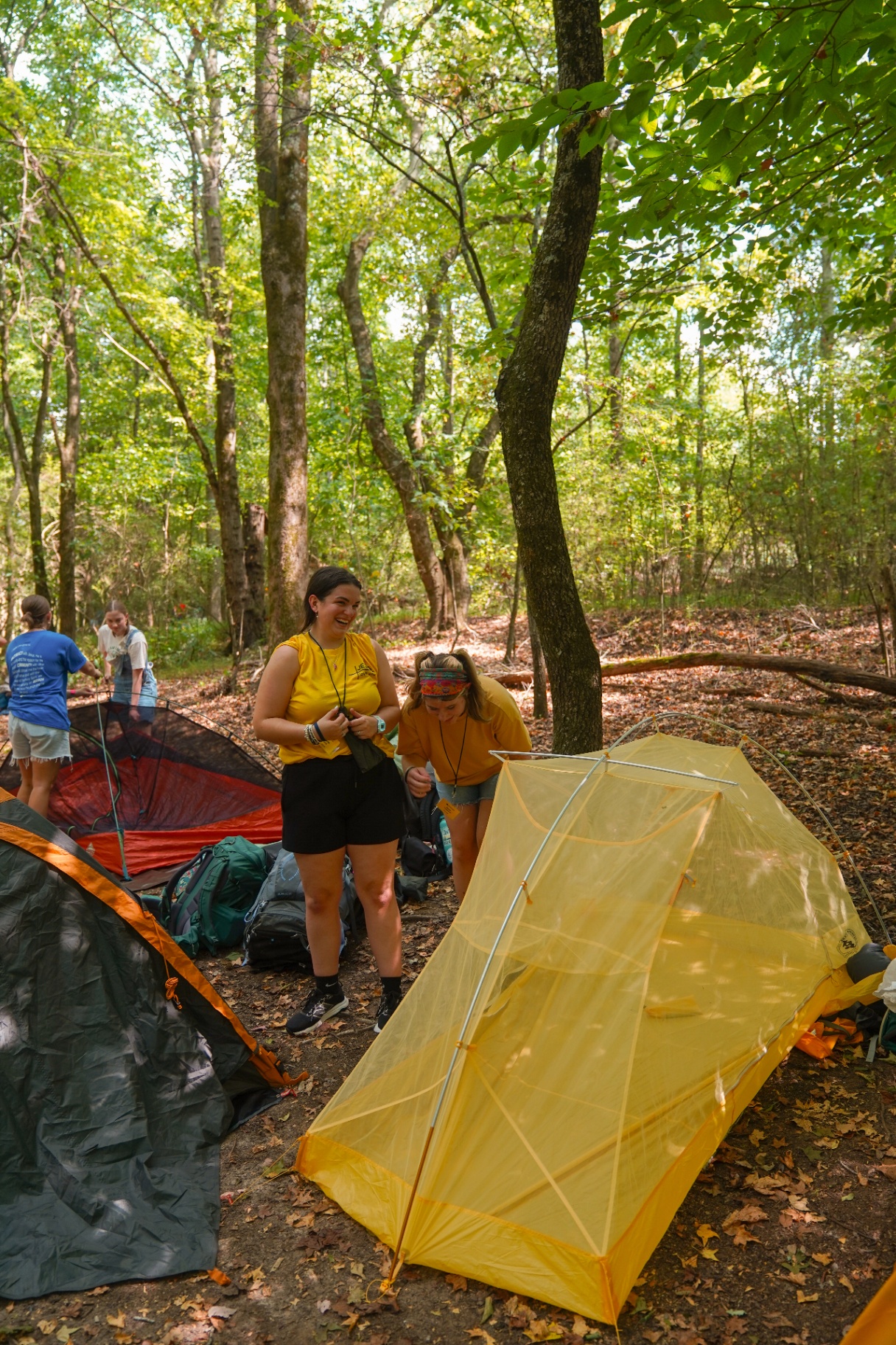 Racers laughing while setting up tents in the woods at training camp