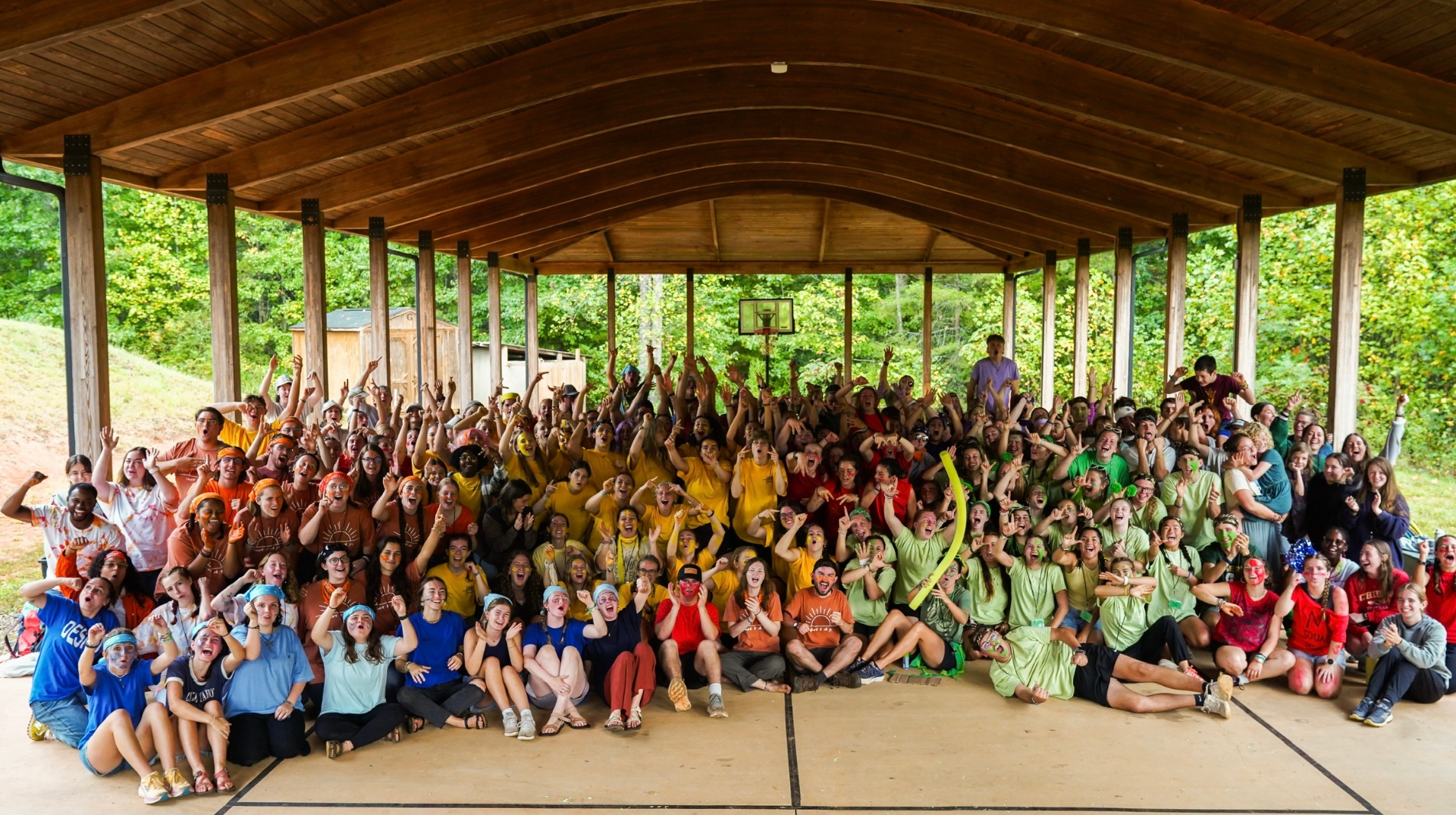 The full training camp group together under the pavilion, arms raised and cheering