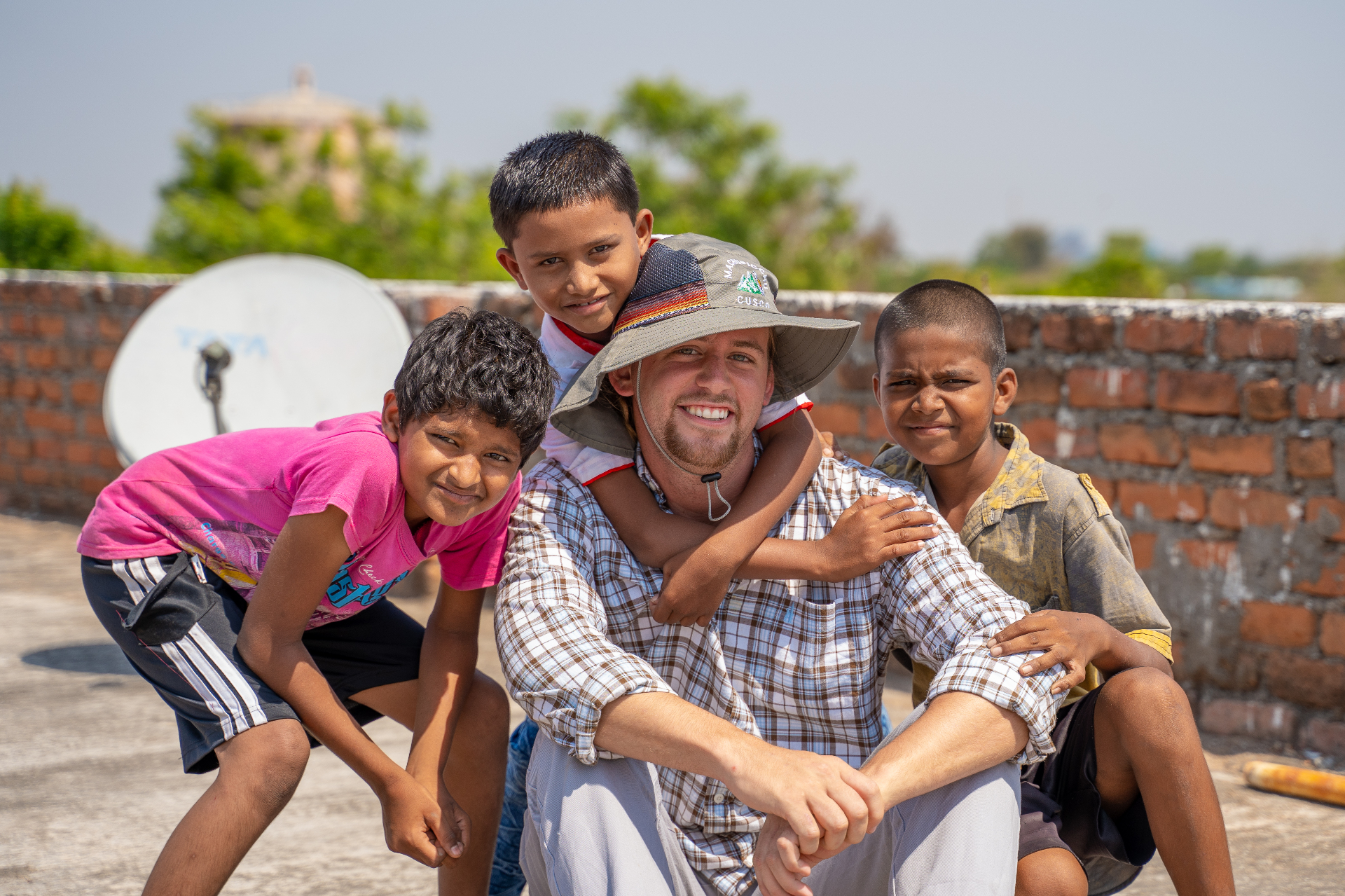 World Race participant with three local boys on a rooftop