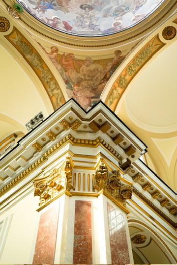 Ornate frescoed ceiling and gilded column inside an Italian church