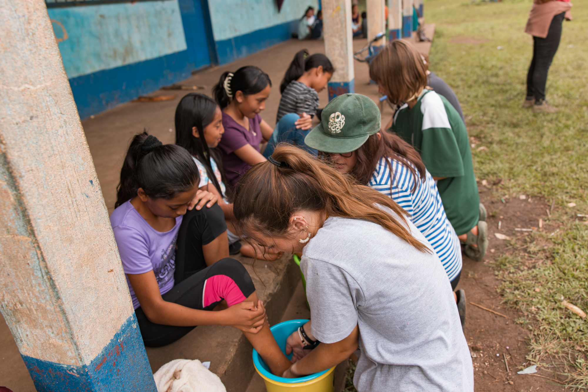 Racers washing a Guatemalan girl's feet during a care and prayer moment