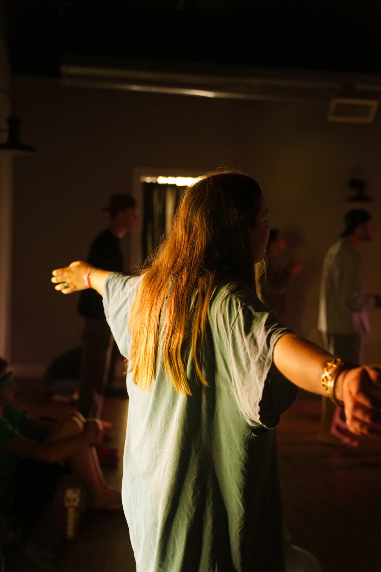 A racer in worship with arms wide open in a candlelit room