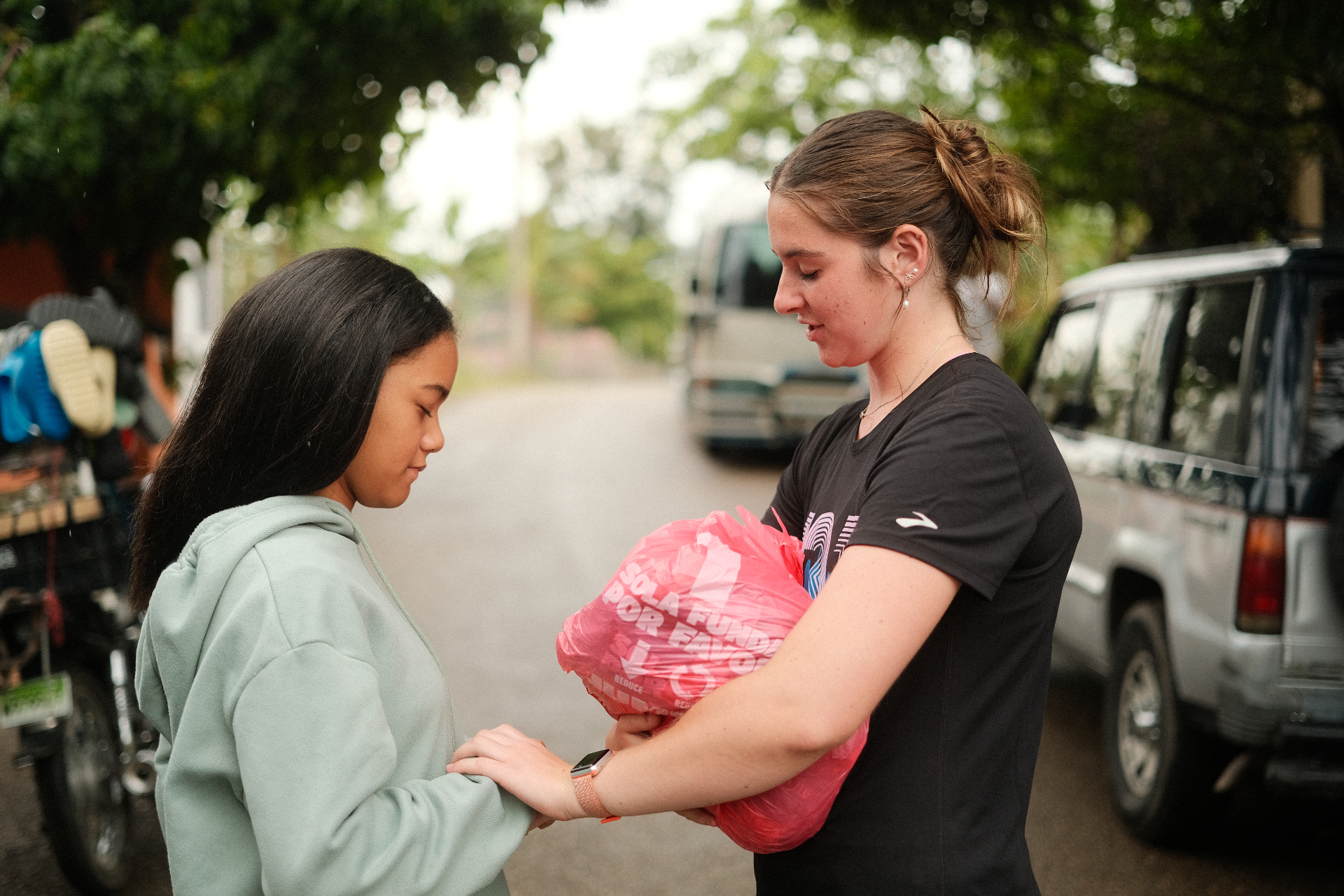 Racer praying with a young girl on a street in the Dominican Republic