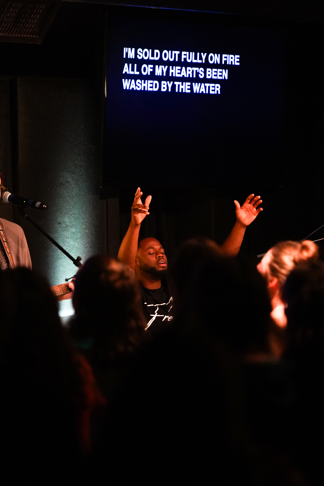 Worship during training camp with a leader singing and hands raised in the room