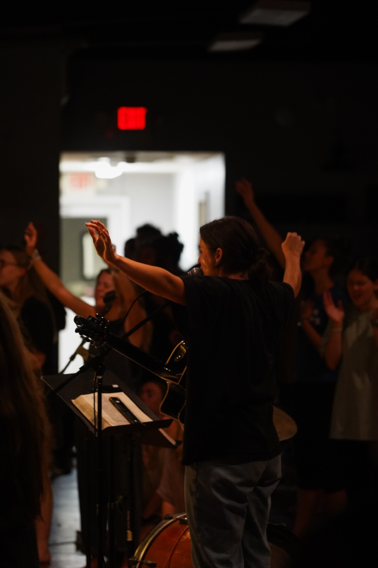 A worship leader with arms raised during a night service