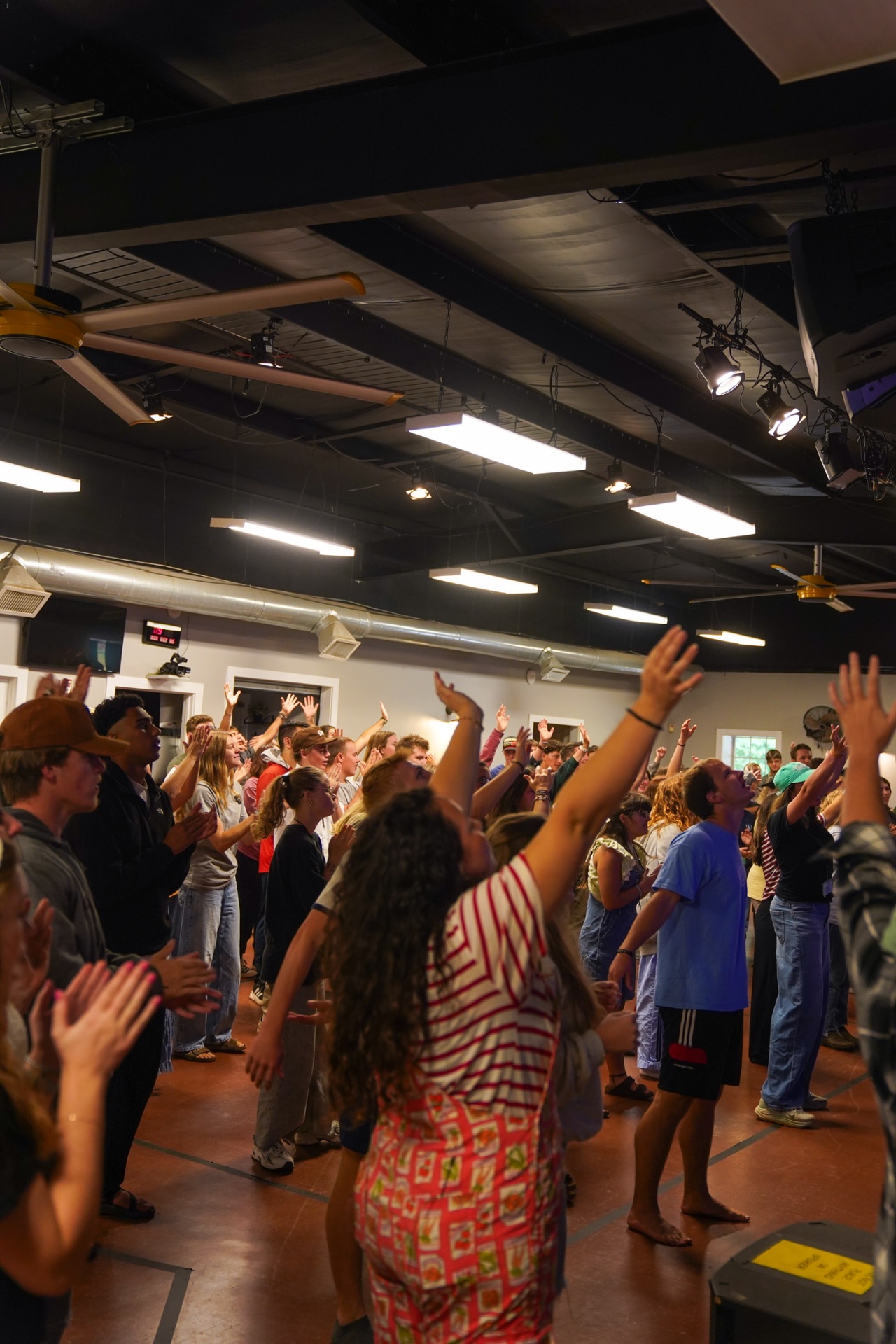 Racers with hands raised during worship at training camp
