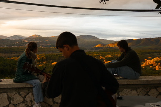 Racers playing guitar at sunset overlooking the Italian countryside