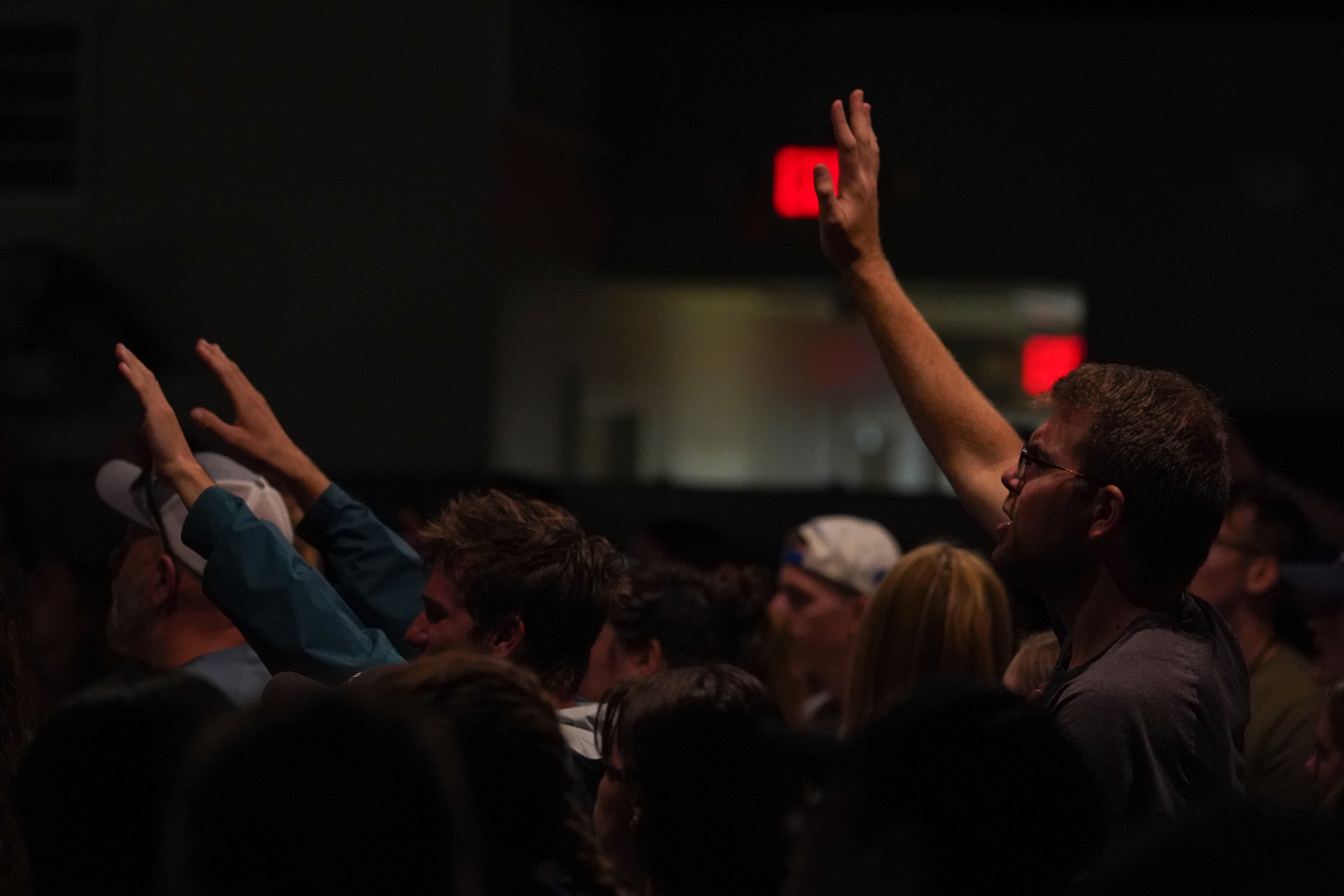 Racers in a worship gathering with hands raised together