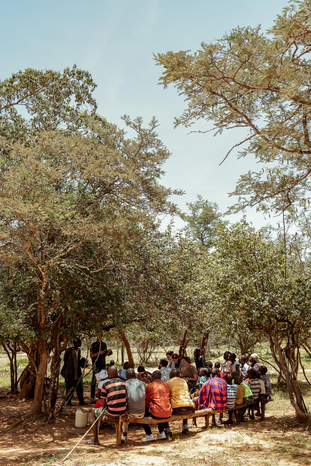 Racers teaching a community gathered under acacia trees in Kenya