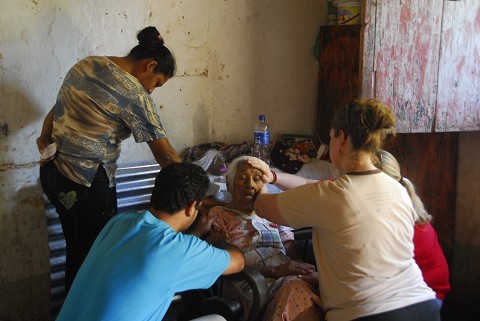 World Race team praying over an elderly woman in her home