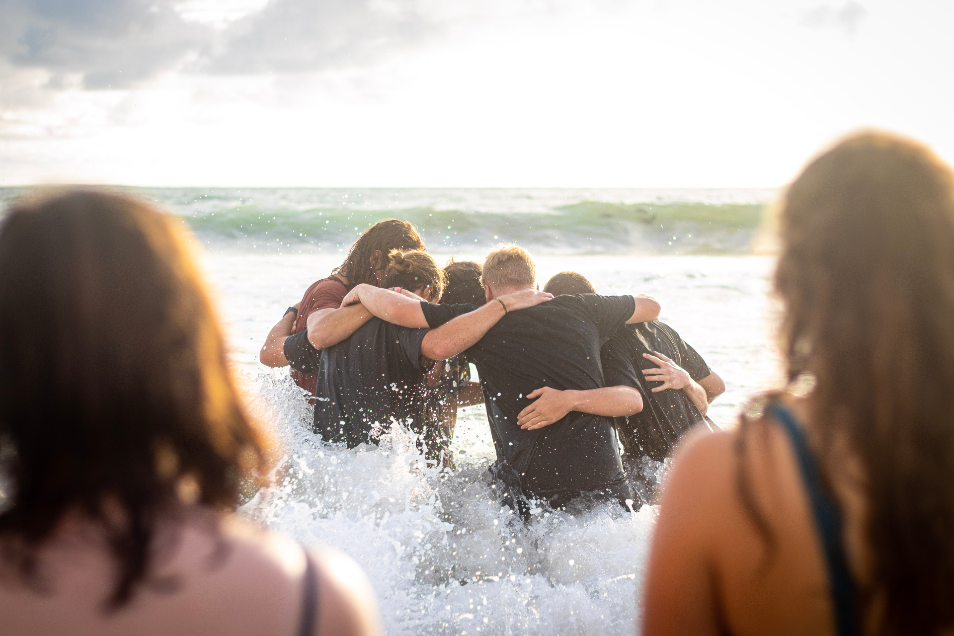 Racers huddled in prayer in the surf at sunset in Costa Rica