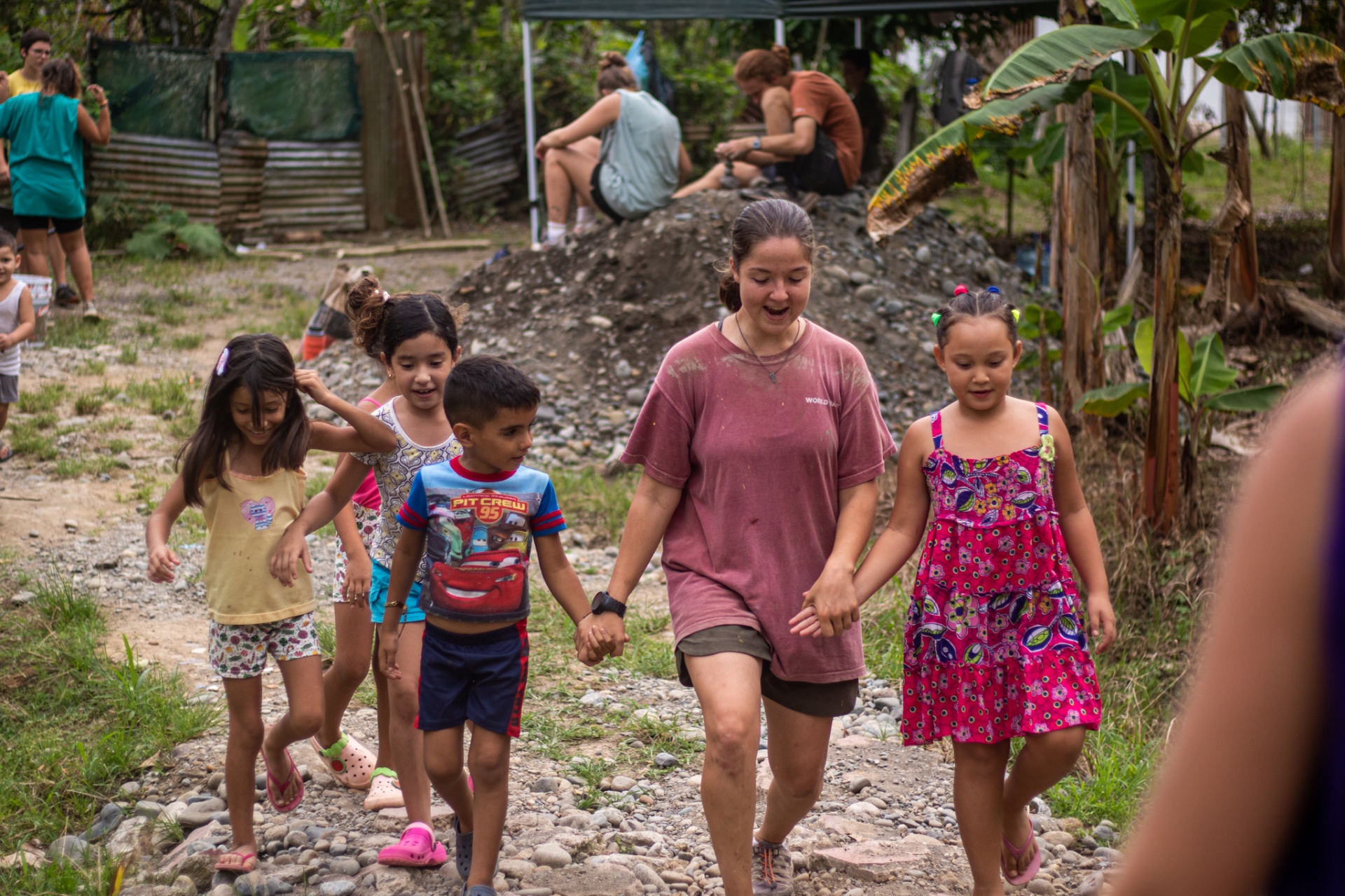 Racer walking hand in hand with Costa Rican children down a gravel village road