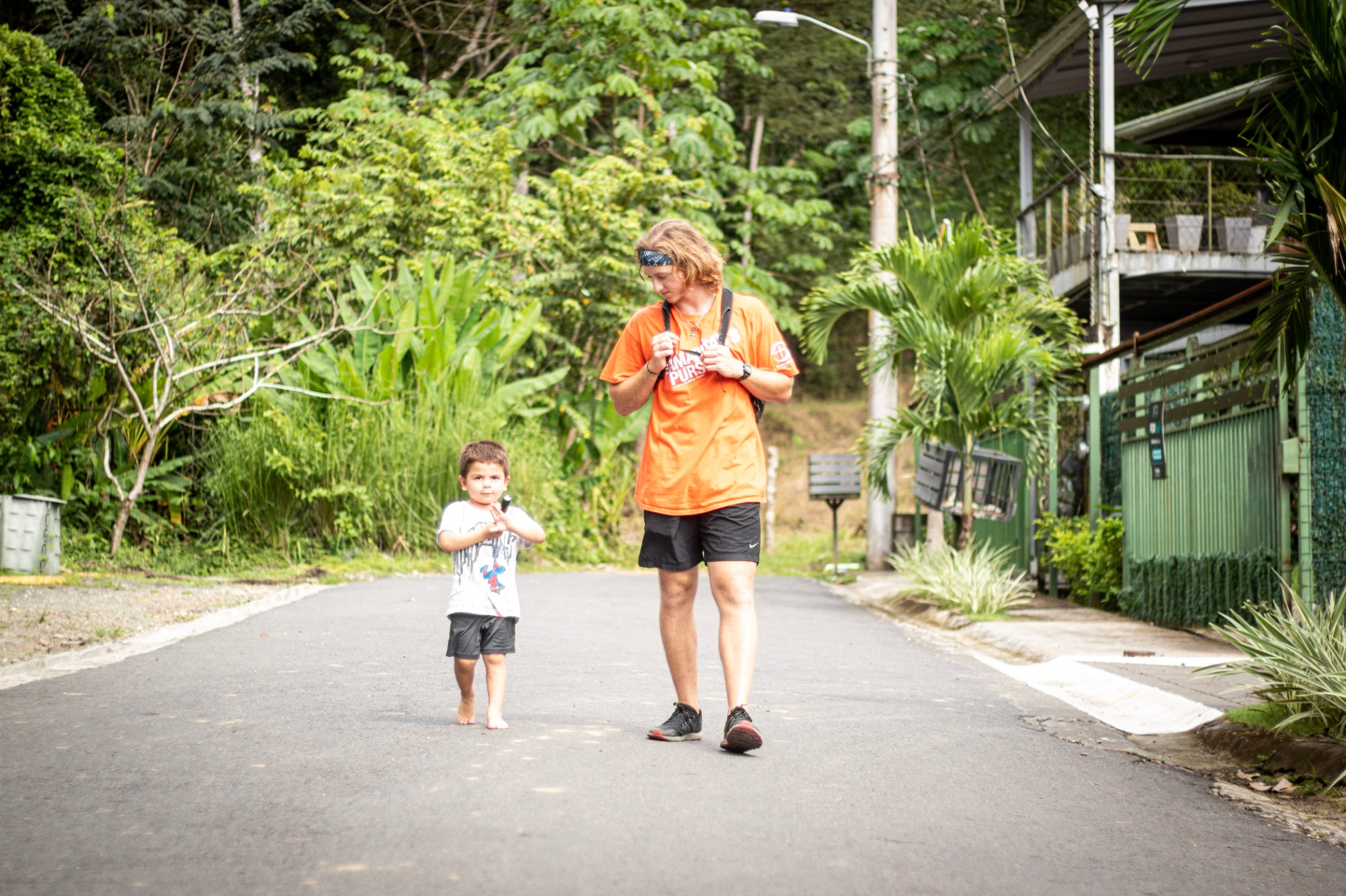 Racer walking with a barefoot Costa Rican toddler down a jungle road