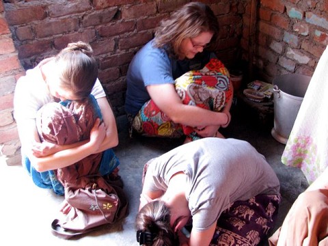 Racers praying with women in an Indian home