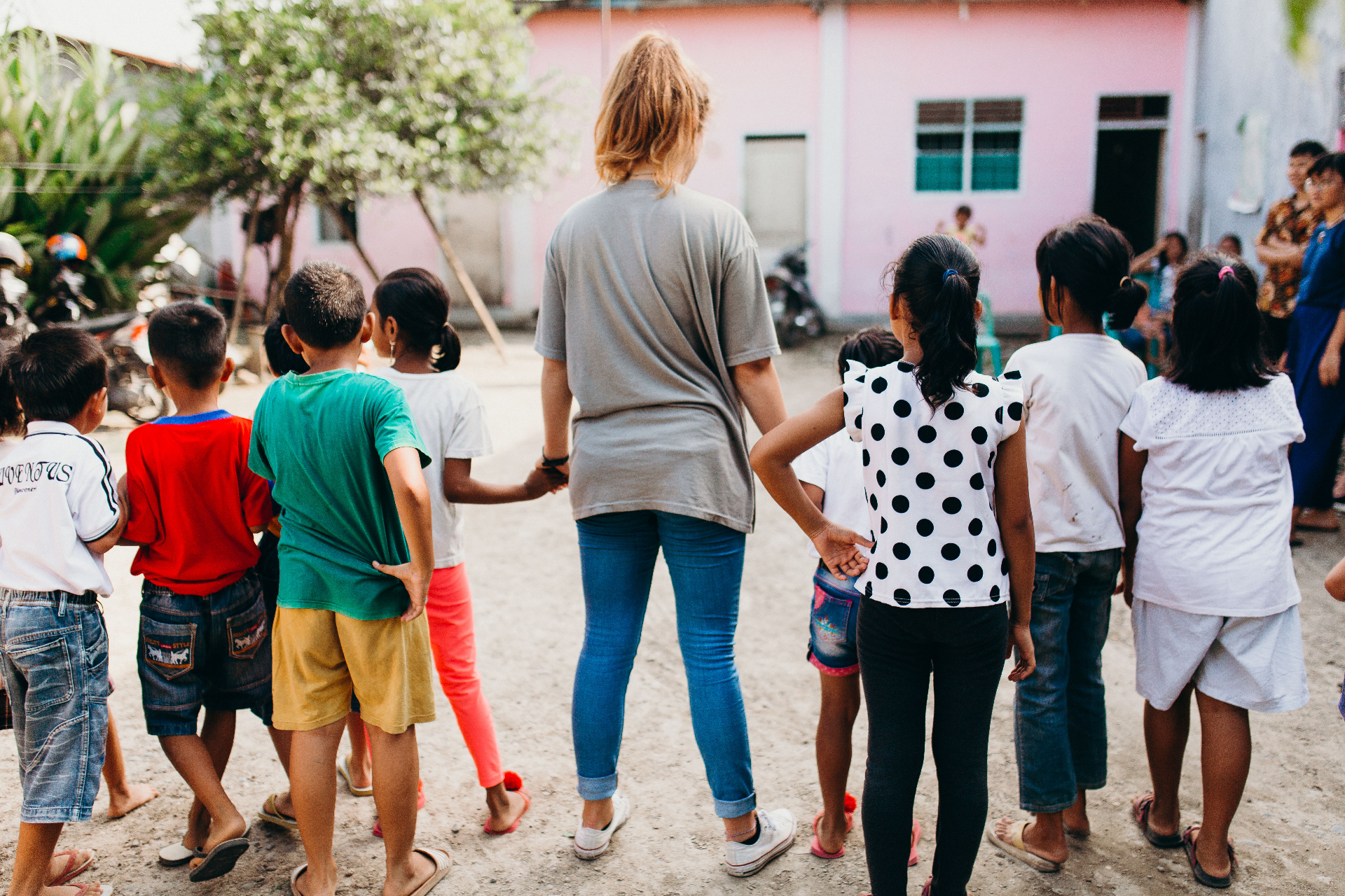 Racer standing in a circle holding hands with Indonesian children