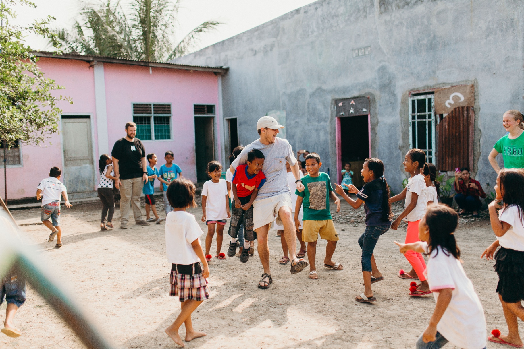 Racer playing games with a crowd of Indonesian kids in a village courtyard
