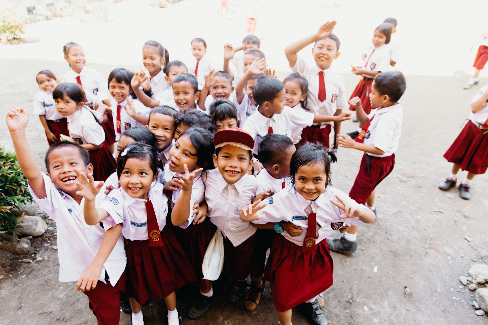 Indonesian schoolchildren in red and white uniforms waving and smiling