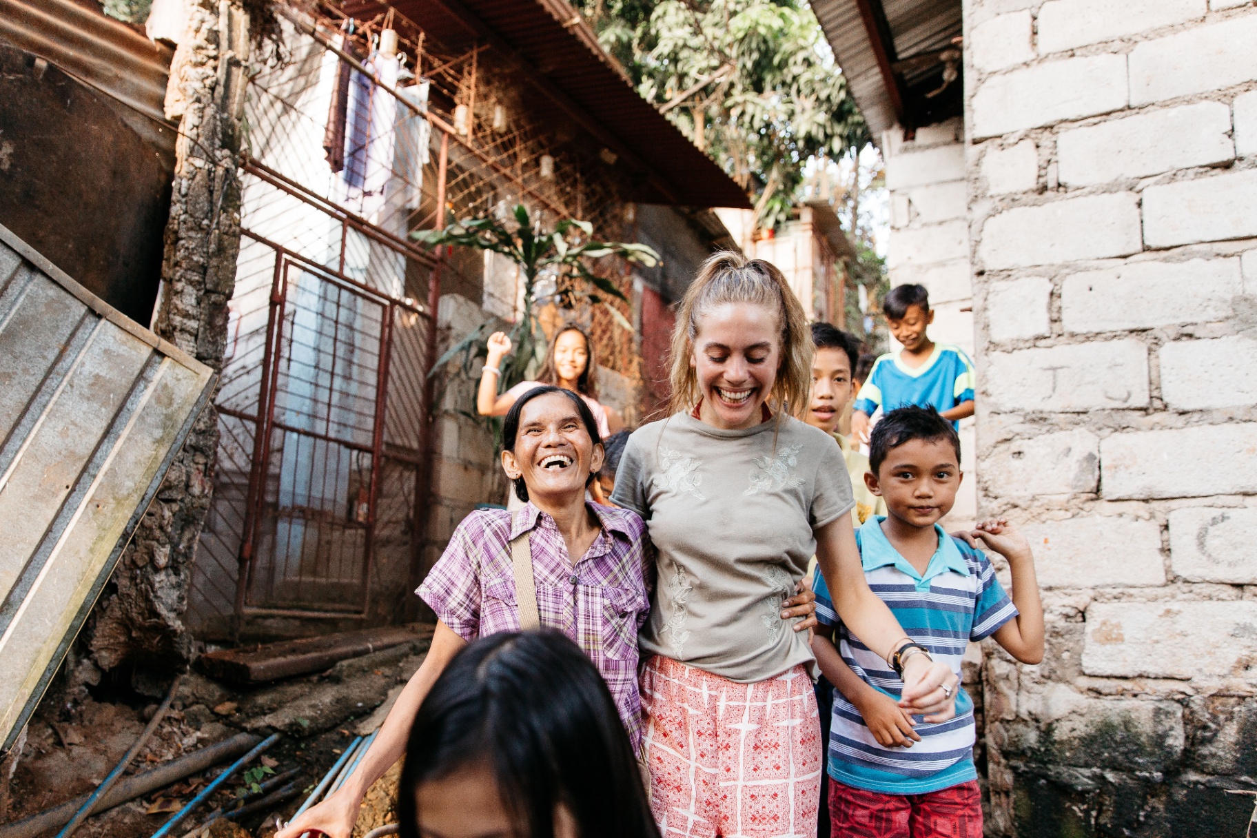Racer laughing with a Filipina woman and children in their neighborhood