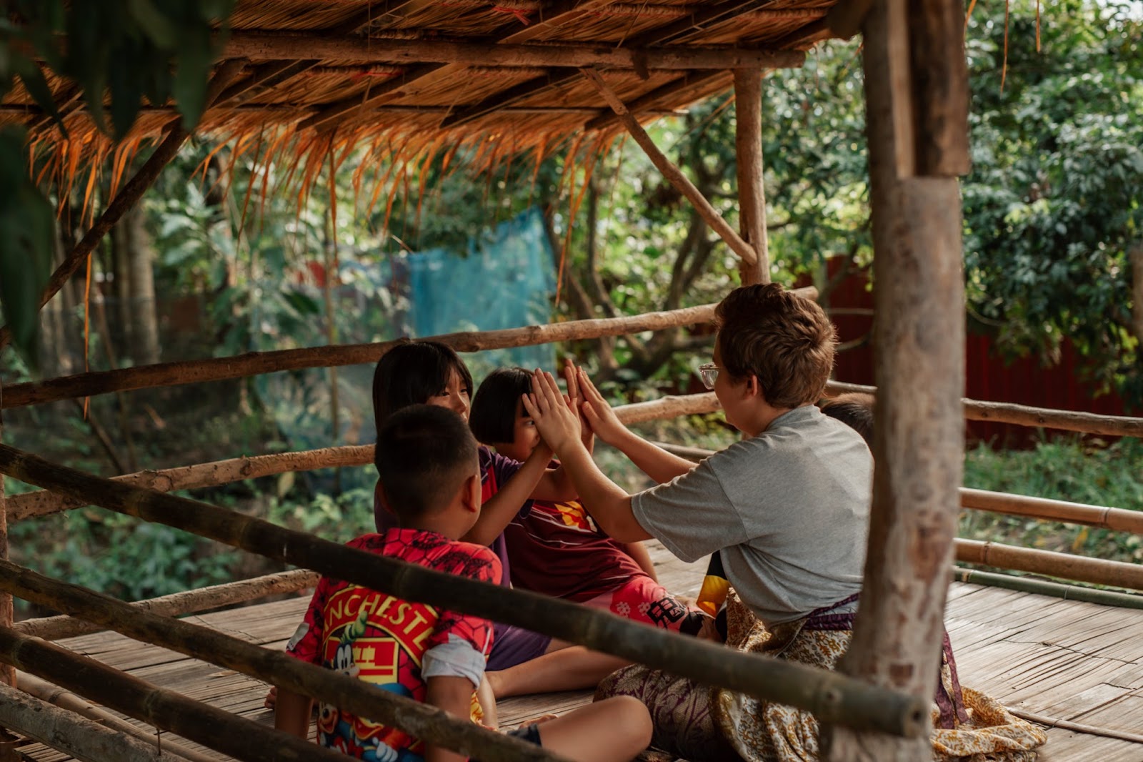Racer high-fiving Thai children in a bamboo hut