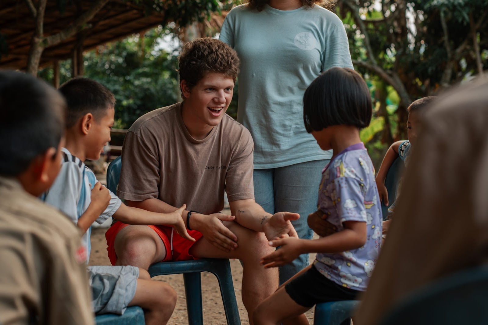 Racer laughing with Thai children seated in a circle