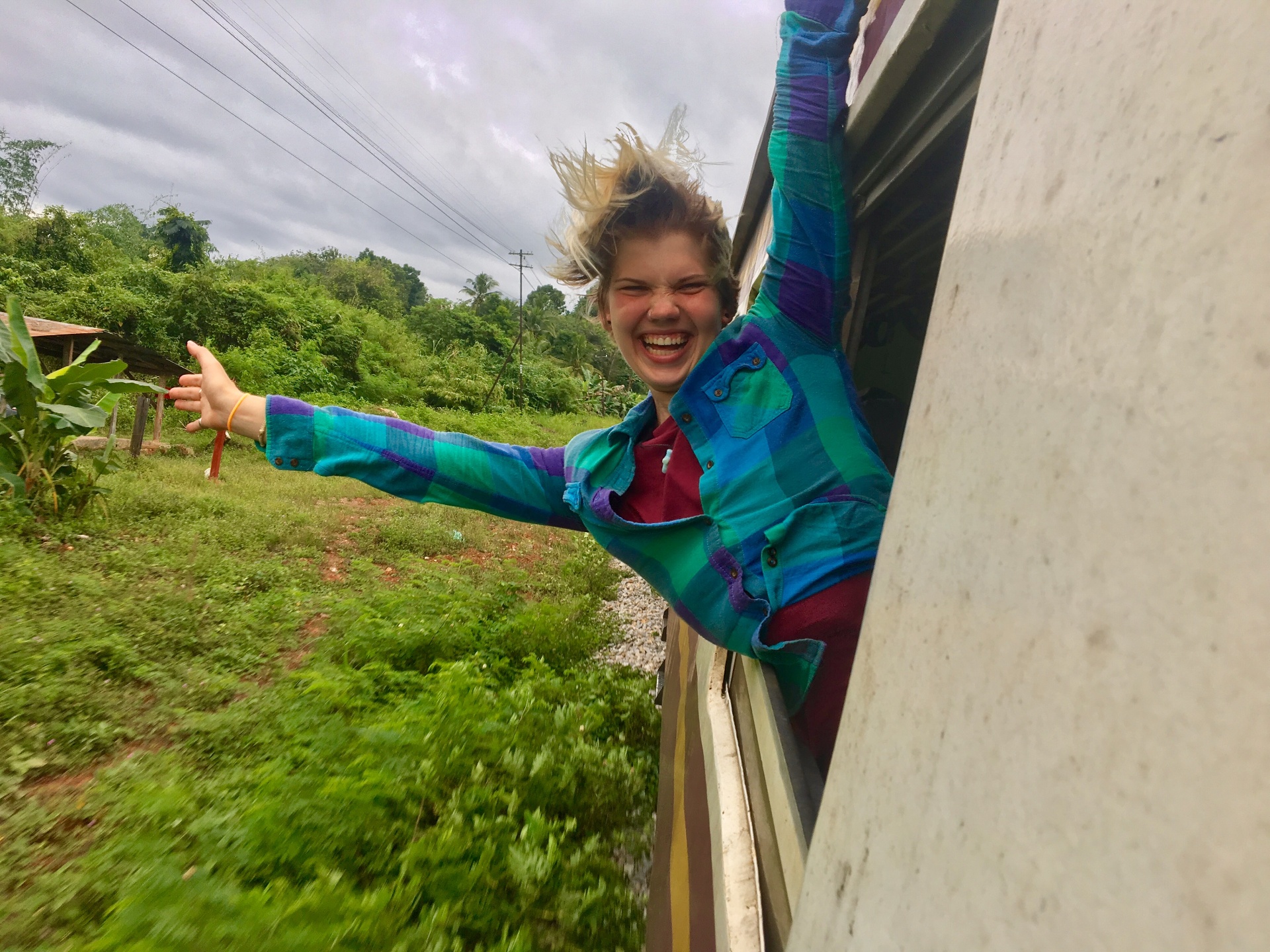 Racer leaning out a moving train window in Thailand