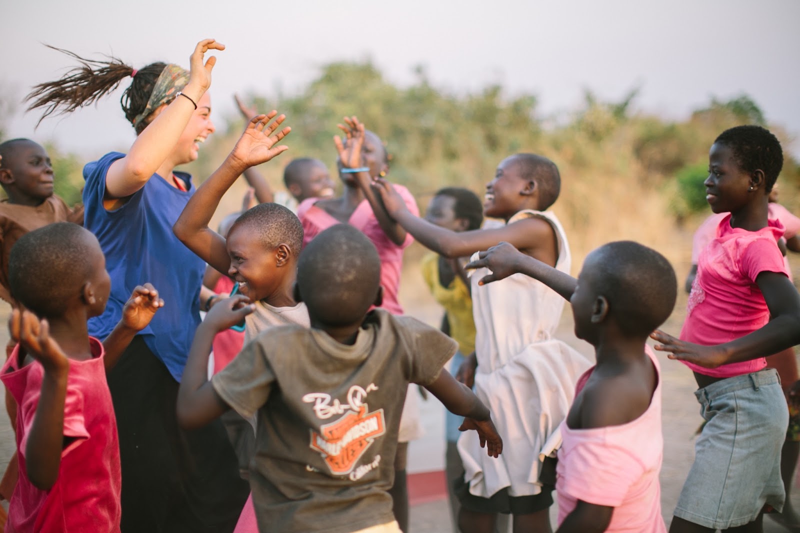 Racer dancing with Ugandan children at sunset
